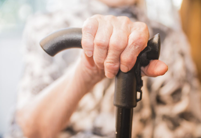 Une personne agée prenant appui sur une canne